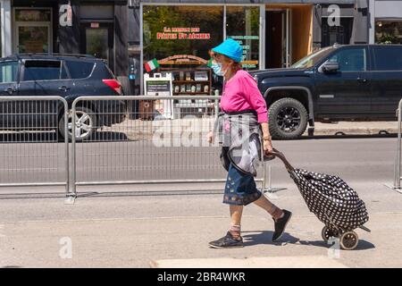 Montreal, CA - 20 May 2020: Woman with face mask for protection from COVID-19 walking down Mont-Royal avenue Stock Photo