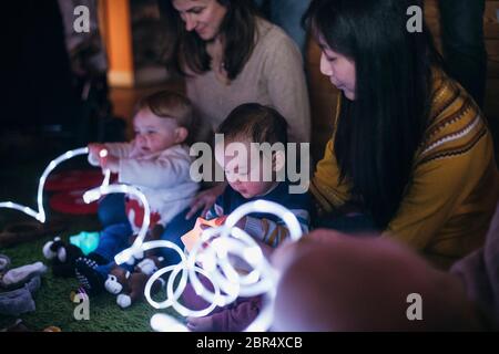 Mother and baby sensory play group are using LED lighting and toys for developmental play. Stock Photo