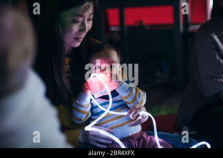 Mother and baby sensory play group are using LED lighting and toys for developmental play. Stock Photo