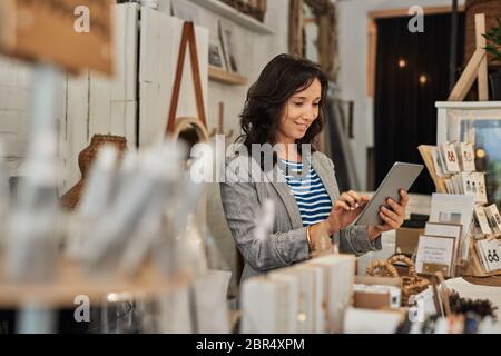 Smiling young Asian woman using a tablet in her shop Stock Photo