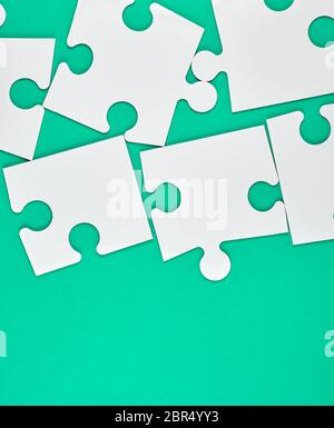 blank white big puzzles on green background, copy space Stock Photo