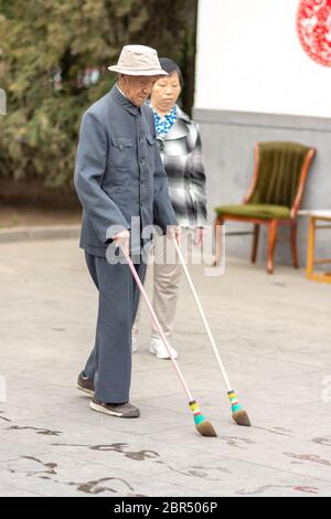 Beijing / China - March 15, 2015: Elderly man practicing water calligraphy (ground writing - dishu) in a park. Water calligraphy is popular pastime am Stock Photo