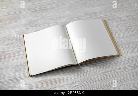Opened blank square book on light wood table background. Stock Photo