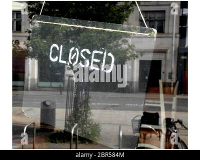 Closed sign in city centre business window with empty streets reflected in glass. Coronavirus pandemic lockdown. 19th May 2020. Exeter, Devon UK Stock Photo
