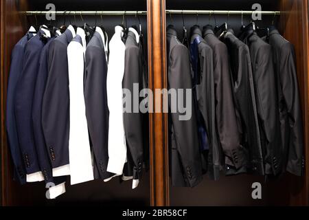 Many men's suits on a hanger in the store Stock Photo
