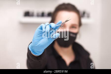 Manicurist shows cuticle scissors in his hands close-up Stock Photo