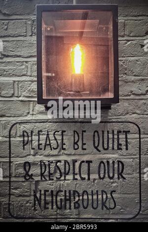 Sign on a pub wall reading 'Please be quiet and respect our neighbours'. Stock Photo