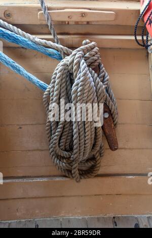 Old ropes coiled around a rusted metal cleat on an old fishing boat, vertical aspect Stock Photo