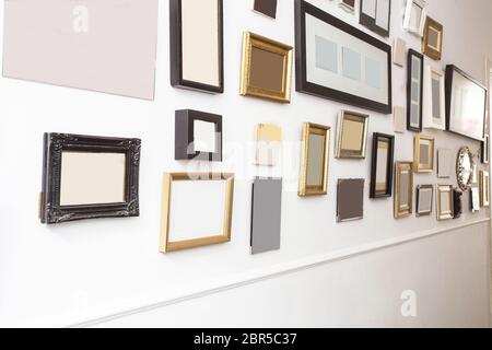 various many blank small picture frames on white wall, vintage retro design close-up Stock Photo