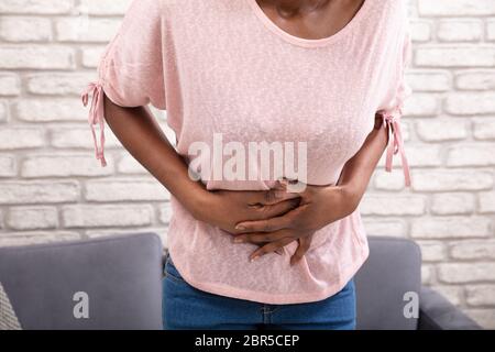 Young Woman Suffering From Stomachache At Home Stock Photo