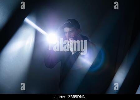 Male Security Guard In Black Uniform Using Walkie-talkie And Flashlight Stock Photo