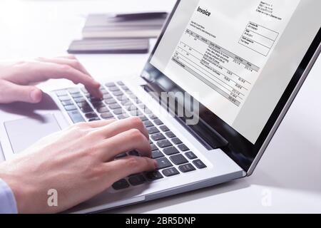 Close-up Of A Businessman's Hand Checking Invoice On Laptop Stock Photo