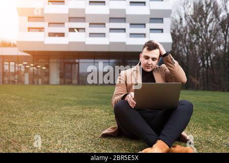 Man hold his head while working on a laptop Stock Photo