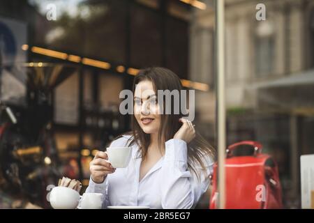 Portrait of a beautiful girl drinking coffee in a cafe window Stock Photo