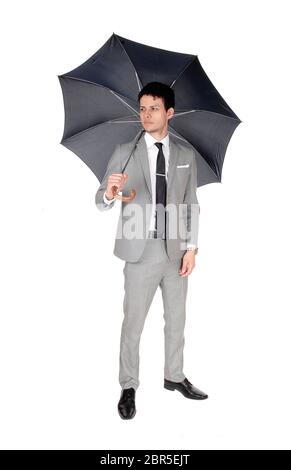 A handsome young business man standing in a light gray suit and an open umbrella, isolated for white background Stock Photo
