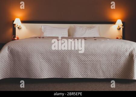 Romantic bed in a beautiful hotel room. Large bed with rose petals for a romantic evening Stock Photo