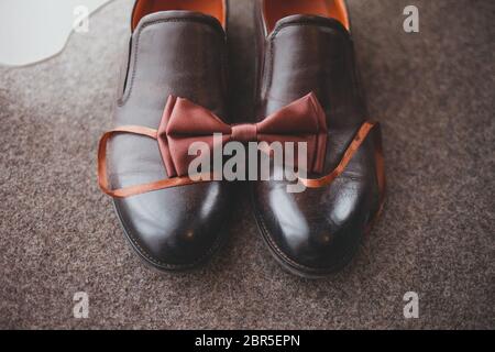 Wedding shoes men with bowtie. Bowtie lies on leather shoes. Marriage accessories concept Stock Photo