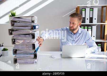 Businessperson Pushing Paper Documents Away And Working With Digital Documents On Computer Instead Stock Photo