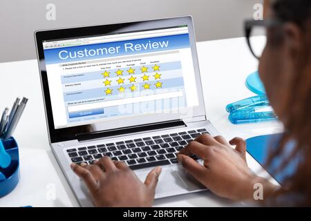 Close-up Of A Businesswoman's Hand Filling Customer Review Form On Laptop Screen Stock Photo