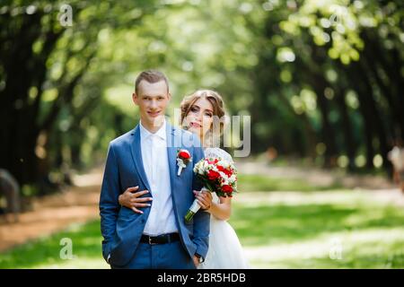 Fabulous young wedding couple posing in the park on the sunny day. Stock Photo