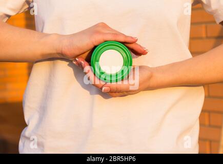 Green jar of honey or cream in women's hand. Space for your logo. Stock Photo