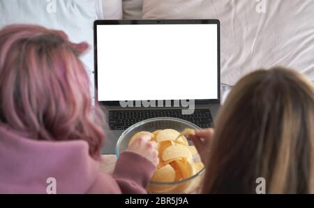Two teen girls friends watch tv movie series online on laptop mock up screen. Stock Photo