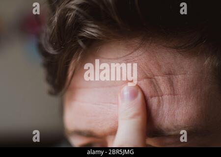 A close up shot of a man rubbing his forehead with one finger. Stock Photo