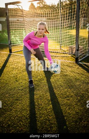 Teen female goalie catching a shot during a soccer game Stock Photo