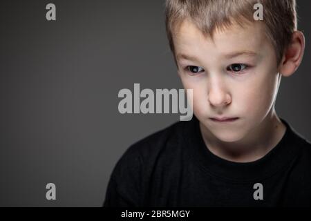 Grief-stricken little boy - feeling intense sorrow, remorse, sadnesss - studio portrait - vivid emotions series Stock Photo