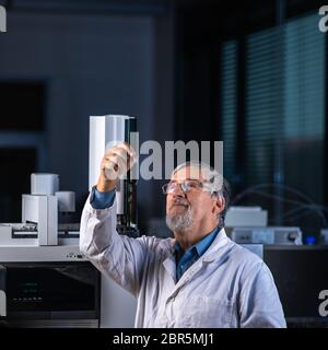 Senior scientist in a chemistry lab carrying out research - looking at gas chromatography samples, preparing the analysis on a modern gas chromatograp Stock Photo