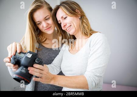 Mother and daughter taking photos and checking them on a modern digital DSLR camera Stock Photo