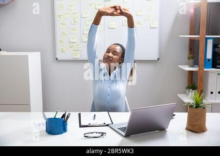 Young Businesswoman Stretching Her Arms In Office Stock Photo
