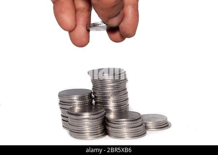 A businessman putting coins over a stack of coins. Financial, economy, investment and savings concept. Banking and exchange object. Close up view. Stock Photo