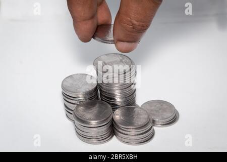 A businessman putting coins over a stack of coins. Financial, economy, investment and savings concept. Banking and exchange object. Close up view. Stock Photo
