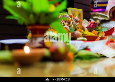Selective focus. Diwali puja or Laxmi puja set up at home. Oil lamp or diya with crackers, sweet, dry fruits, indian currency, flowers and statue of G Stock Photo