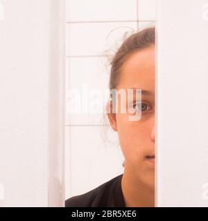 Close up half face portrait teenager girl looking through white metal bars, self-awareness and self worth concept, square image Stock Photo
