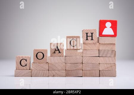 Red Human Figure Block Next To Word Life Coach On Wooden Block Stock Photo