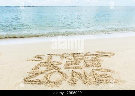 Close-up Of Stress Free Zone Written On Sand Near The Sea At Beach Stock Photo