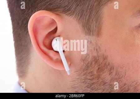 Close-up Of Man Listening To Music Uses Modern Wireless Earphone Stock Photo