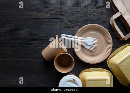 Disposable takeaway food boxes and tableware on dark wooden background. Nature friendly kitchen utensil. Stock Photo