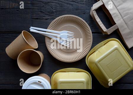 Disposable takeaway food boxes and tableware on dark wooden background. Nature friendly kitchen utensil. Stock Photo