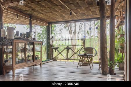 Interior Design Room of Home Stay Include Showcase and Rattan Chair in Country Style. Interior design room at floor 1 with tree and plants. Living roo Stock Photo