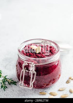 Beetroot pesto or hummus. Homemade beet pesto sauce in glass jar and fresh thyme on dark black background. Copy space for text. Ideas and recipes for Stock Photo