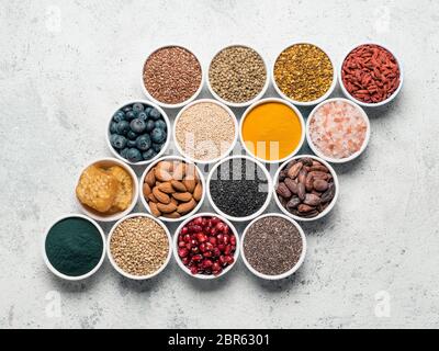 Various superfoods in smal bowl gray concrete background. Creative layout of superfood as chia, spirulina, raw cocoa bean, goji, hemp, quinoa, bee pol Stock Photo