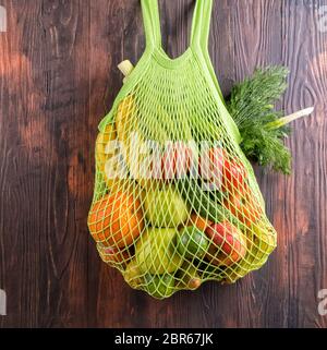 Fresh fruits in string shopping bag on wooden table. Stock Photo
