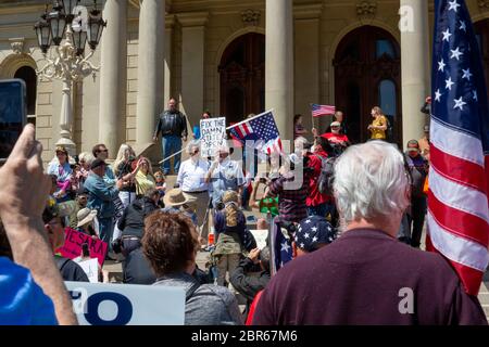 Lansing, Michigan, USA. 20th May, 2020. Karl Manke, a Owosso, Michigan barber, speaks to a rally as barbers give free haircuts on the lawn of the Michigan State Capitol. Manke opened his barbershop in defiance of Gov. Gretchen Whitmen's emergency orders during the coronavirus pandemic. The resulting protest, called Operation Haircut, was organized by the Michigan Conservative Coalition. Credit: Jim West/Alamy Live News Stock Photo