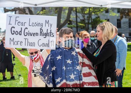 Lansing, Michigan, USA. 20th May, 2020. Barbers give free haircuts on the lawn of the Michigan State Capitol to protest Governor Gretchen Whitmer's emergency orders which keep many businesses closed during the coronavirus pandemic. Republican State Senator Kevin Daley sat for a haircut. The protest, called Operation Haircut, was organized by the Michigan Conservative Coalition. Credit: Jim West/Alamy Live News Stock Photo