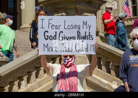 Lansing, Michigan, USA. 20th May, 2020. Barbers give free haircuts on the lawn of the Michigan State Capitol to protest Governor Gretchen Whitmer's emergency orders which keep many businesses closed during the coronavirus pandemic. The protest, called Operation Haircut, was organized by the Michigan Conservative Coalition. Credit: Jim West/Alamy Live News Stock Photo