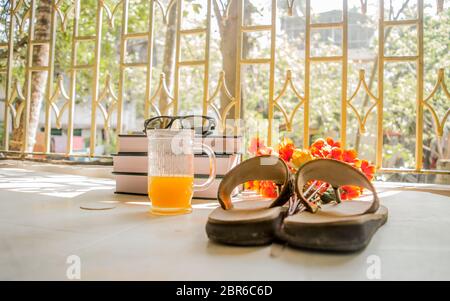 Modern women holiday essential for sunday summer time weekend activities on wooden table. Sunglasses placed over Books, flip flops, cocktail glass and Stock Photo