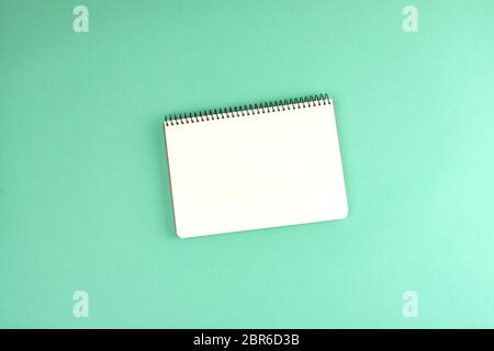 open spiral notebook with clean white sheets on a green background, top view Stock Photo